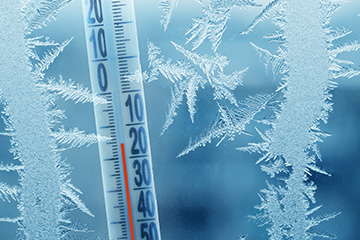 Frost forming on a pane of glass with a thermometer displaying temperatures on -15C